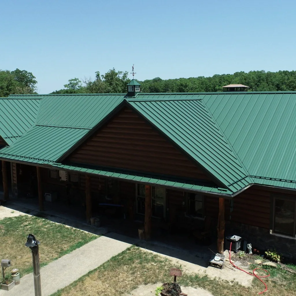 Green standing seam metal roof on a log home in mid-Missouri